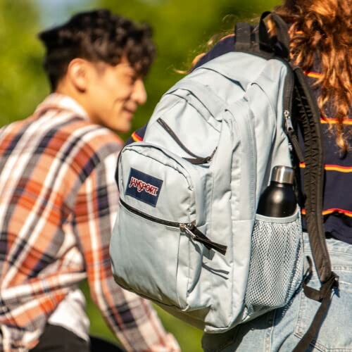 Two people outdoors, one with a light blue backpack.